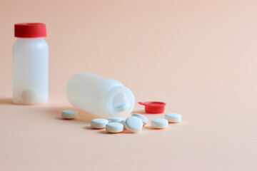 Medication, rounded white tablets and small bottles on a light background.