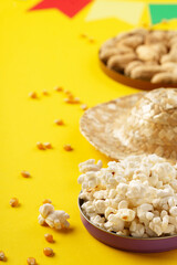 Festa Junina Summer Festival concept. Brazilian straw hat, popcorn, peanuts and colorful flags on yellow background for Brazilian Festa Junina Summer Festival