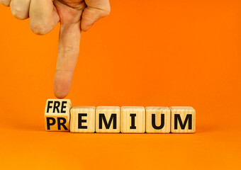 Premium or freemium symbol. Businessman turns wooden cubes and changes the concept word Premium to Freemium. Beautiful orange table orange background. Business premium or freemium concept. Copy space.