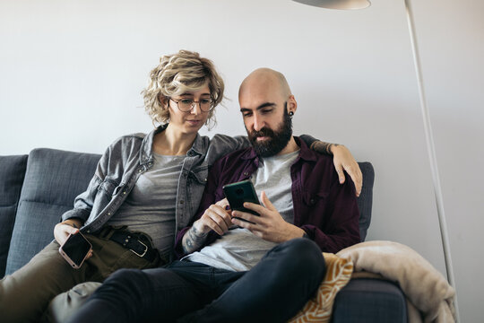 Couple sitting on sofa using mobile