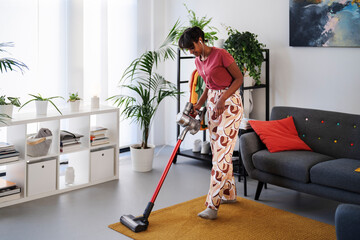 Ethiopian female cleaning floor with vacuum cleaner