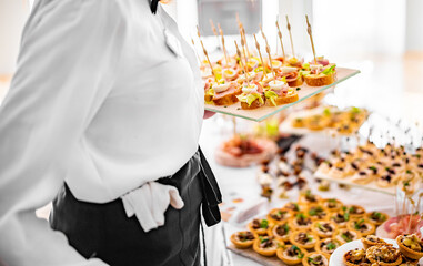 woman hands of a waiter prepare food for a buffet table in a restaurant