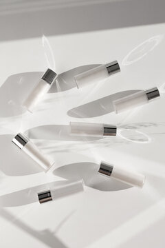 White and silver cosmetics package, different shadows on a white table