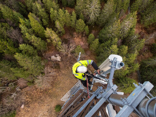 A technician on a telecommunication tower, 5G fiber optic antenna