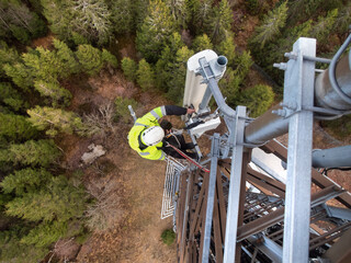 A technician on a telecommunication tower, 5G fiber optic antenna