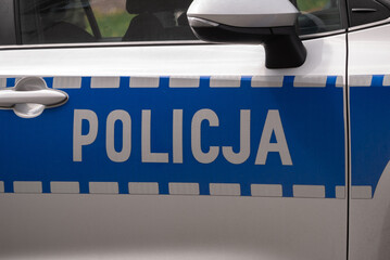 Police car side door sign, letters in Polish language, Policja means Police. © Longfin Media