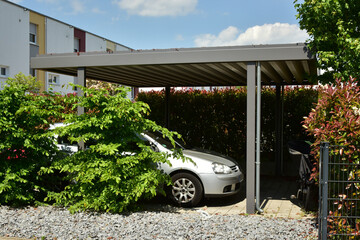 Moderner Carport mit Metalldach und Stahlträgerkonstruktion im Einfahrtsbereich eines Wohnhauses