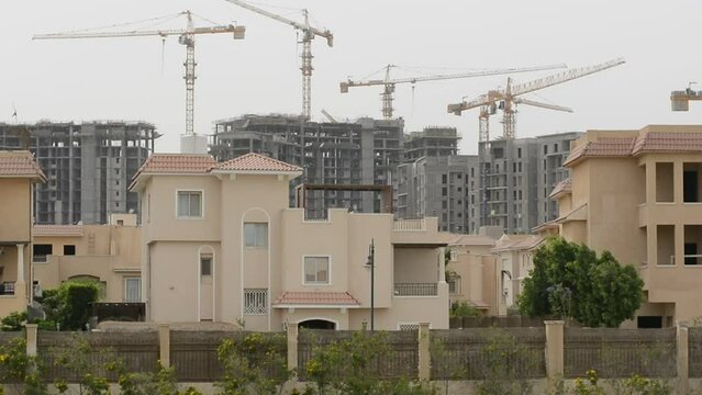 Construction site of new buildings in Egypt, acres of luxurious real estate residential buildings under construction with cranes, selective focus