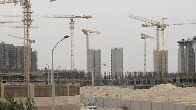 Construction site of new buildings in Egypt, acres of luxurious real estate residential buildings under construction with cranes, selective focus
