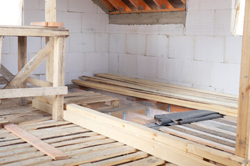 Construction of the floor on the second floor of the garage from wooden boards. White foam concrete walls