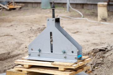 Device for bending gray metal pipes on boards on the background of the earth