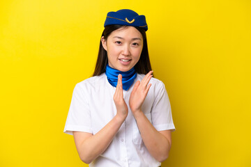 Airplane Chinese woman stewardess isolated on yellow background applauding after presentation in a conference