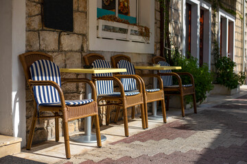 Fototapeta na wymiar Empty mediterranean outdoor cafe with brown chairs and yellow tables