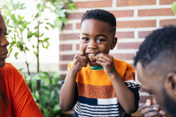Little boy eating chicken with his hands