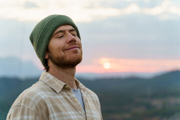 Portrait of happy man in nature at sunset with closed eyes
