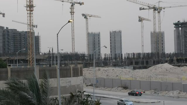Construction site of new buildings in Egypt, acres of luxurious real estate residential buildings under construction with cranes, selective focus