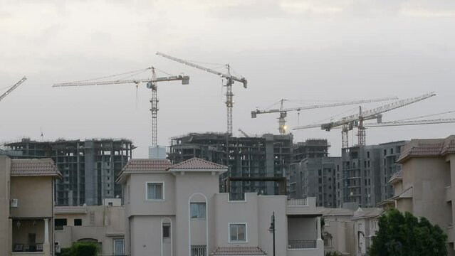 Construction site of new buildings in Egypt, acres of luxurious real estate residential buildings under construction with cranes, selective focus