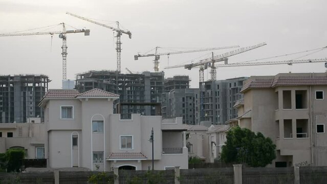 Construction site of new buildings in Egypt, acres of luxurious real estate residential buildings under construction with cranes, selective focus