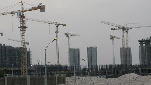 Construction site of new buildings in Egypt, acres of luxurious real estate residential buildings under construction with cranes, selective focus