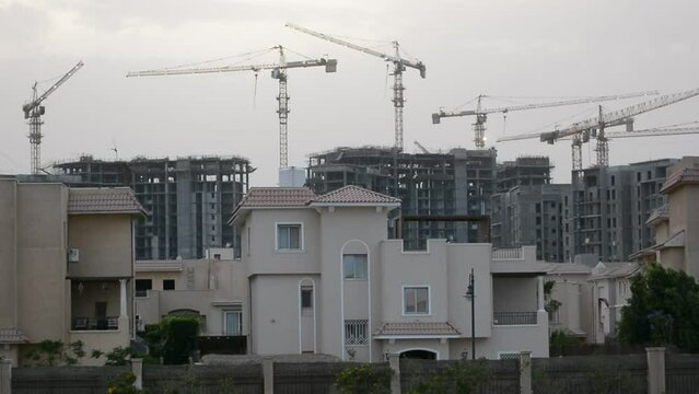 Construction site of new buildings in Egypt, acres of luxurious real estate residential buildings under construction with cranes, selective focus