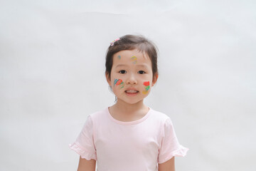 The naughty little girl covered her hands and face with paint