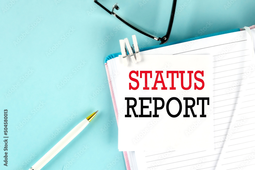 Poster status report text on a sticky on notebook with pen and glasses , blue background