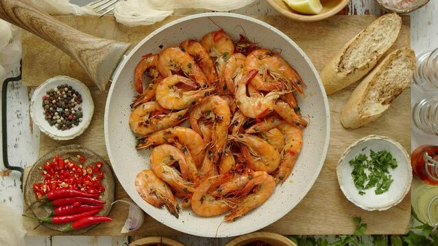 Traditional fried tiger prawn with garlic bread as top view served in a white frying pan