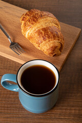 Croissant with a cup of full coffee, directly above	