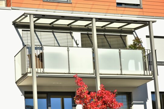 Balkon mit Metallgeländer als Sturzsicherung und Mattglas-Platten als Sichtschutz