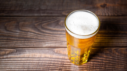 Cold craft  light Beer is pouring from bottle on wooden Table