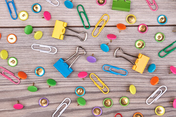 Collection of various type of paper clips on white wood. Set of multicolored stationery clips.