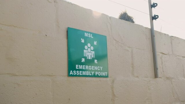 Green sign indicates designated area as emergency assembly point