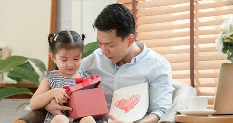 Happy Asian young father surprise with red gift box and heart colored card which little cute...