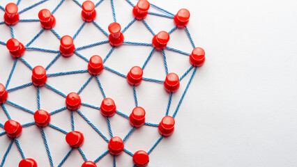 Netzwerk mit vielen Verbindungen mit roten Stecknadeln und Faden
