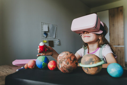 Little girl using VR glasses at home for learning Solar system planets