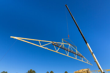Crane holds the wooden roofing truss with crane holds a roof beams for installing