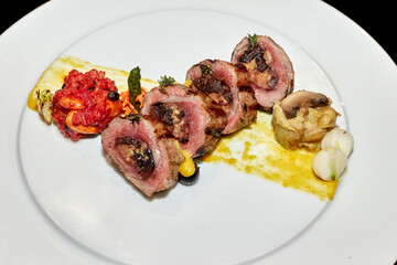 Fried or baked meat for dinner with vegetables and sauce on a black background