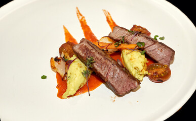 Fried or baked meat for dinner with vegetables and sauce on a black background