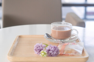 Condensed milk tea or coffee with cookie and flower props served on wooden tray to customers in the...