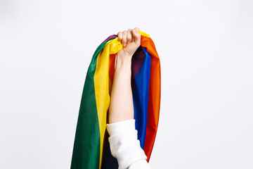 Flag of pride, LGBTQ flag, rainbow flag in female hand on a white background