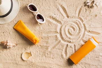 Sunblock, sunglasses and hat on summer sandy beach
