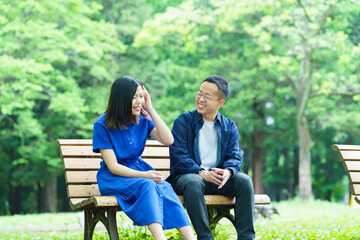 公園のベンチで談笑する若いカップル