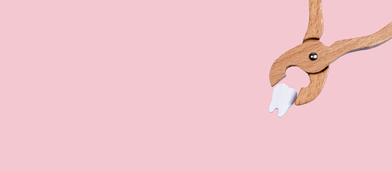 Banner with dental forceps with pulled tooth. Extraction caused by decay, gum disease, injury, impaction, overcrowded teeth. Oral health concerns concept. Copy space on pastel background. photo