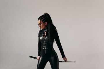 Young woman in tight bodysuit posing with samurai sword katana bushido