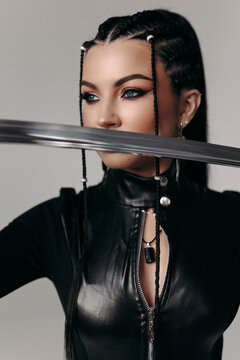 portrait of a beautiful brunette in a tight latex suit with a katana in her hands