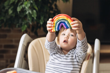 Cute little boy holding in his hands molding colorful rainbow from plasticine. DIY. Children craft....