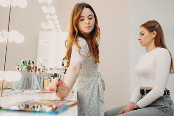 Beautiful young woman applying makeup beauty visage brush.