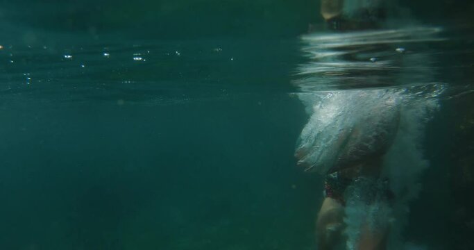 Sports male teenager 10 years in swim shorts jumping from rocky stone into clear Adriatic sea during summer vacation travel. Croatia, Istria