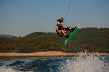 handsome healthy active man masterfully jumping over splashing wave on wakeboard