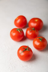 Fresh red tomatoes on gray texture background. Cherry tomatoes with green stems.Fresh vegetables. Place to copy.